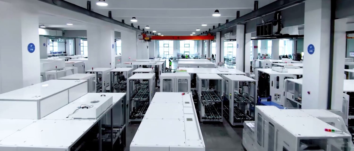 整机装配车间：白色设备成排，行车覆盖全跨